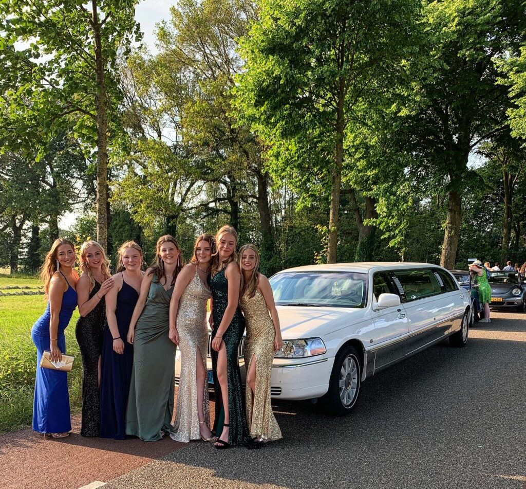 Group of girls by limousine outdoors.